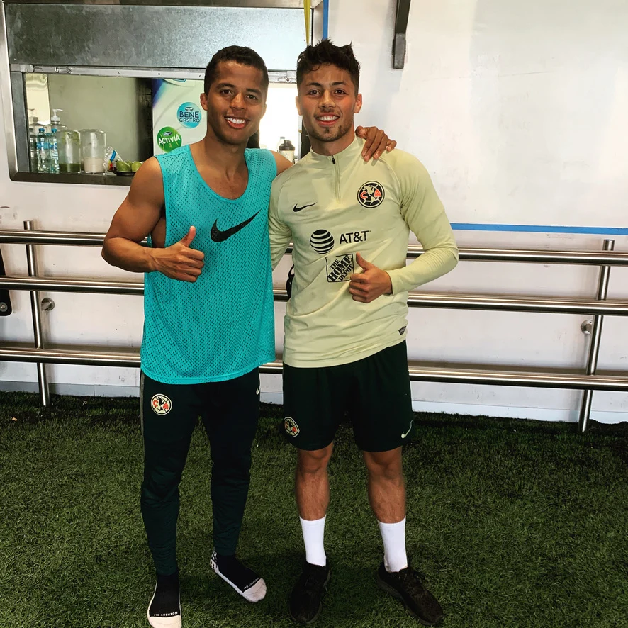 Adrian Goransch con una camiseta de entrenamiento del Club América junto a Giovanni dos Santos, ambos sonriendo con el pulgar arriba